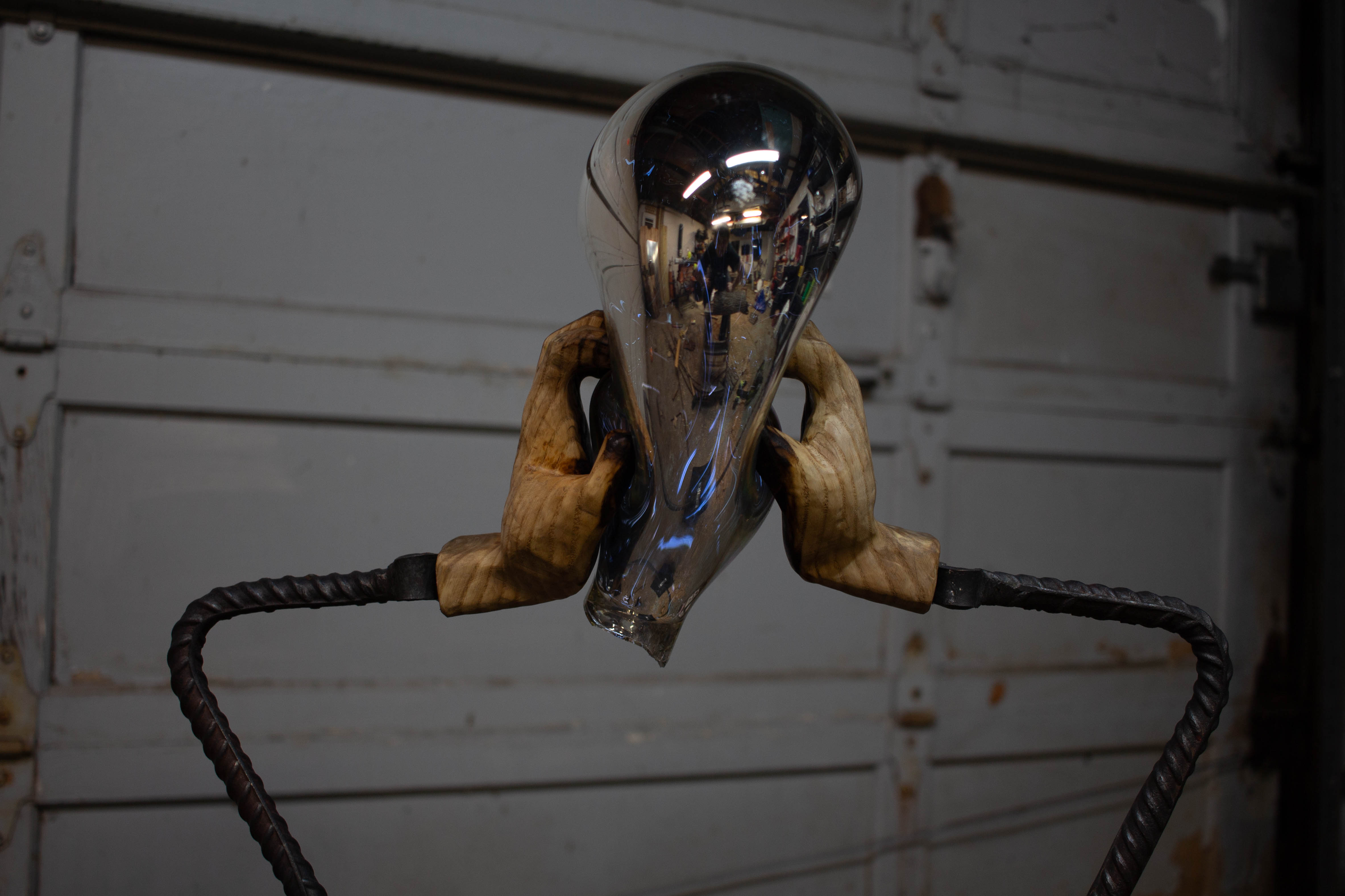 wood hands squishing a glass bubble from the side